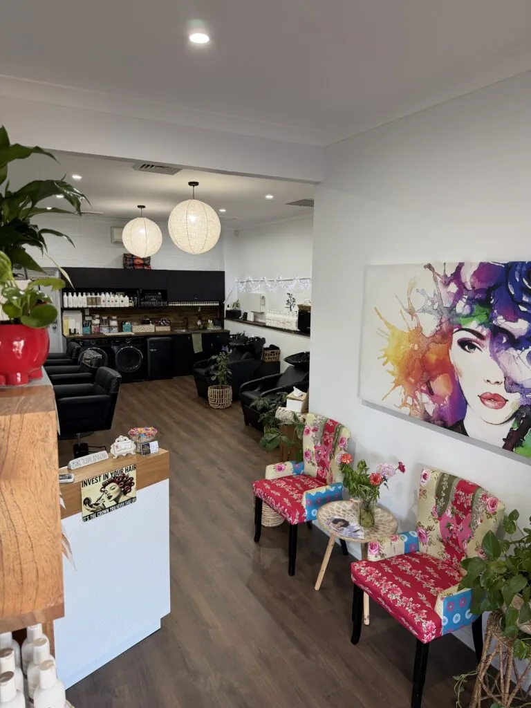 Inside Twisted Scissors Hair Design, with floral chairs, greenery and salon styling stations